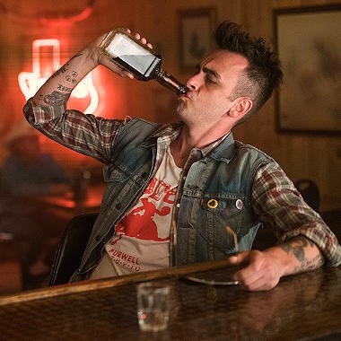 Cassidy sits in a bar, tipping back a bottle of Ratwater whiskey.